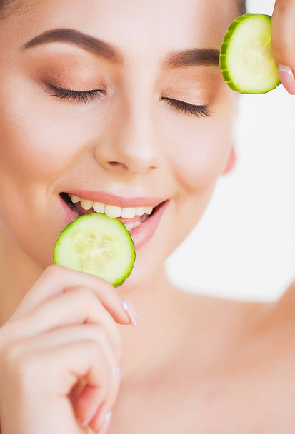 Beautiful young woman with cucumbers on eyes. - Photo, Image