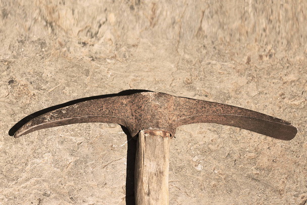 Das Spitzhacke-Werkzeug liegt auf dem Stein. Extraktion von Stein oder Gold Eisen alten rostigen Spitzhacke mit einem Griff. ähnlich - Foto, Bild