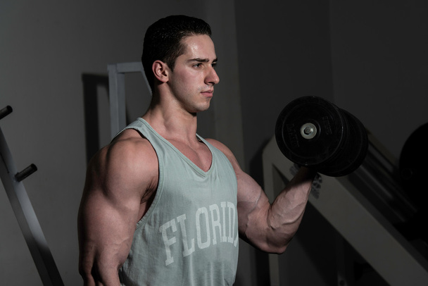 young bodybuilder doing heavy weight exercise for biceps with du - Foto, Imagen