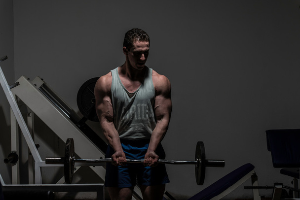 young bodybuilder doing heavy weight exercise for biceps with ba - Fotografie, Obrázek