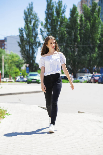 Young beautiful brunette woman in jeans and white blouse walking - Foto, Imagem