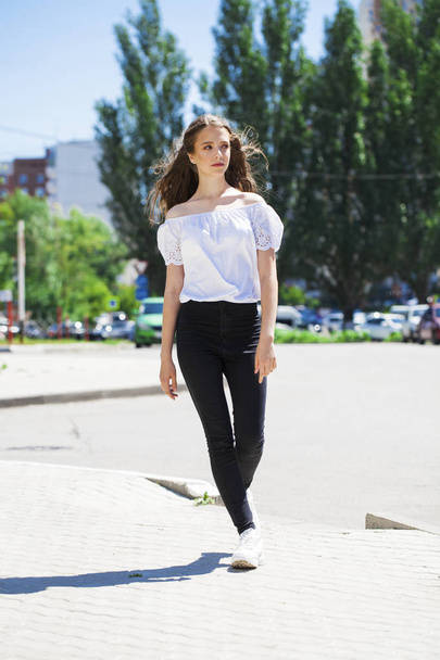 Young beautiful brunette woman in jeans and white blouse walking - Valokuva, kuva