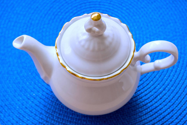 white teapot on a background of blue wicker mat, soft selective focus - Photo, Image