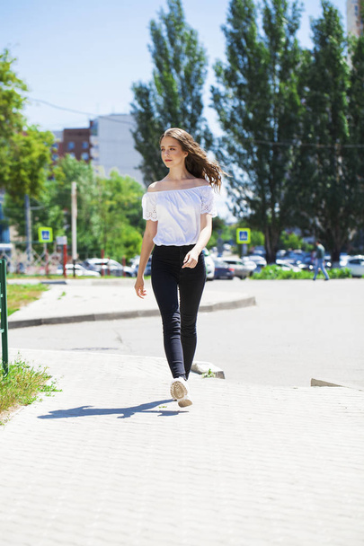 Young beautiful brunette woman in jeans and white blouse walking - Foto, Imagen