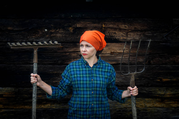 Młoda kobieta stoi z Pitchfork w pobliżu stajni na ranczo. - Zdjęcie, obraz