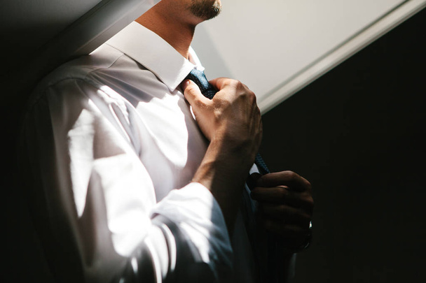 Мужчина выпрямляет галстук
 - Фото, изображение