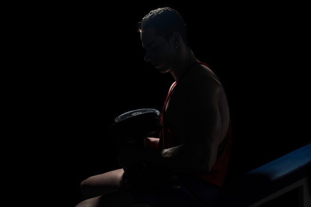 young bodybuilder resting at the bench on black background - Foto, Bild