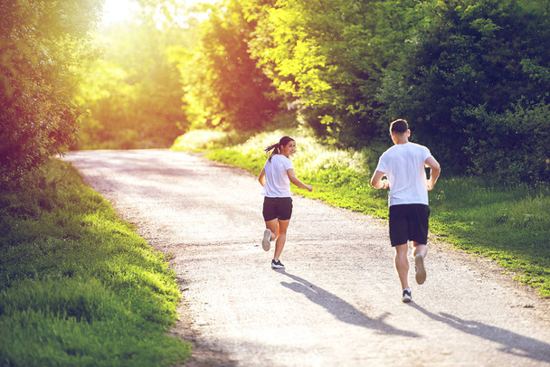 Молодые люди бег трусцой и упражнения в природе, вид сзади
 - Фото, изображение