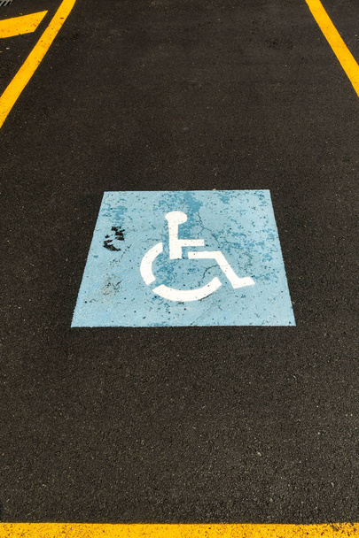 Pyörätuolin symboli, joka on maalattu pysäköintialueen pinnalle osoittamaan pysäköintihallia vammaisille
, - Valokuva, kuva