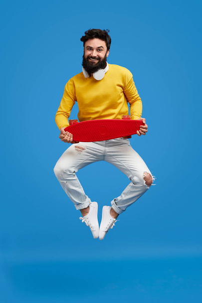 Crazy bearded male jumping with skateboard - Photo, Image
