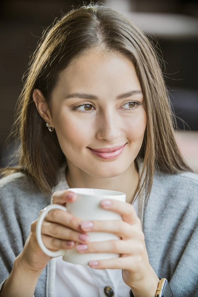 retrato de una hermosa chica con una taza de café en un café
 - Foto, Imagen