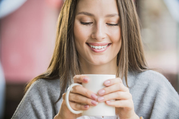 egy szép lány portréja csésze kávéval egy kávézóban - Fotó, kép