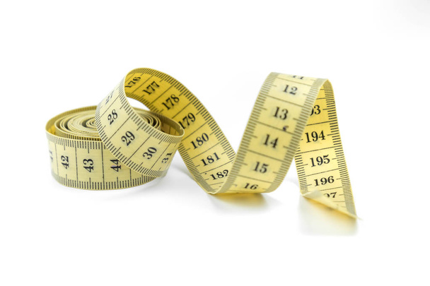 The yellow measuring centimetric tape curtailed by a spiral on a white background. Sewing accessories - Photo, image