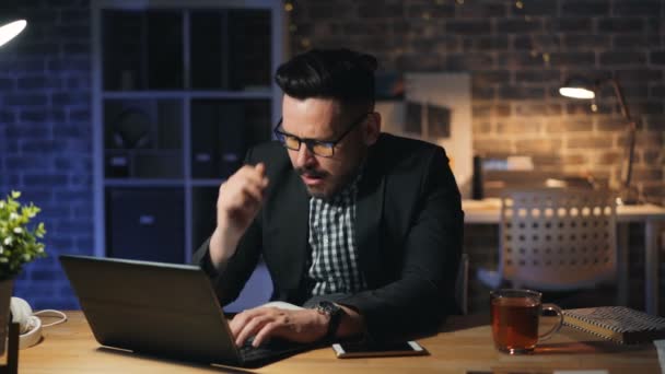 Portrait of exhausted entrepreneur yawning working with laptop in dark office - Video