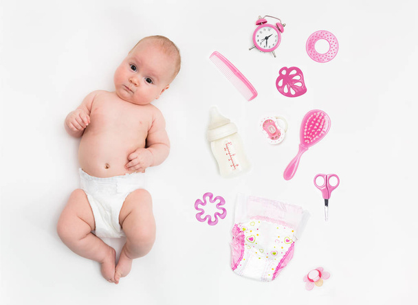 Baby auf weißem Hintergrund mit Kleidung, Toilettenartikeln, Spielzeug und Gesundheitszubehör für Mädchen. Wunschliste oder Einkaufsübersicht für Schwangerschaft und Baby. - Foto, Bild