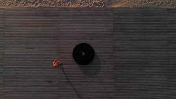 Antenne: flexible Polentänzerin in roter Sportunterwäsche, die bei Sonnenuntergang am Strand auf dem Pylon turnt - Drachen-Tätowierung und akrobatische Gymnastik - Filmmaterial, Video