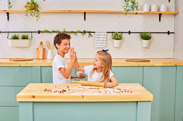 brother and sister are cooking cookies and having fun in the kitchen - Foto, afbeelding