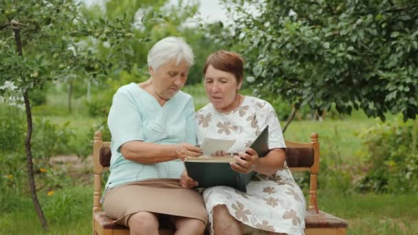 Dwie starsze kobiety patrzą na swoje stare zdjęcia - Materiał filmowy, wideo