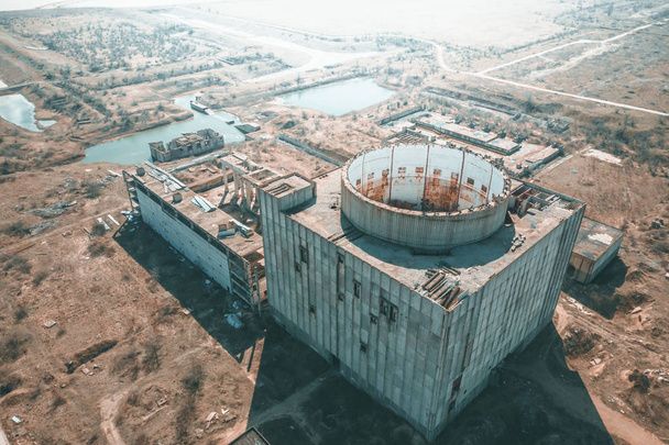 Luchtfoto van verlaten en geruïneerde kerncentrale of station, ronde toren van atoom reactor, groot industrieel gesloopt gebouw - Foto, afbeelding
