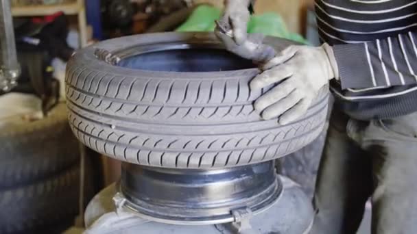 Man auto mechanic oliën band oppervlak op wiel in auto reparatie service buiten. - Video