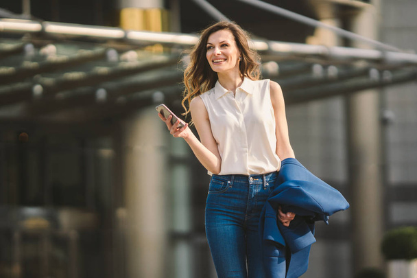 Office buildings city people in suit. Caucasian businesswoman using smartphone with hand. Business concept. Portrait stylish business woman in fashionable clothes holding Phone near office building - Foto, immagini