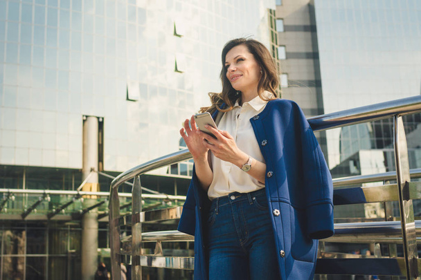 Office buildings city people in suit. Caucasian businesswoman using smartphone with hand. Business concept. Portrait stylish business woman in fashionable clothes holding Phone near office building - Foto, Imagem