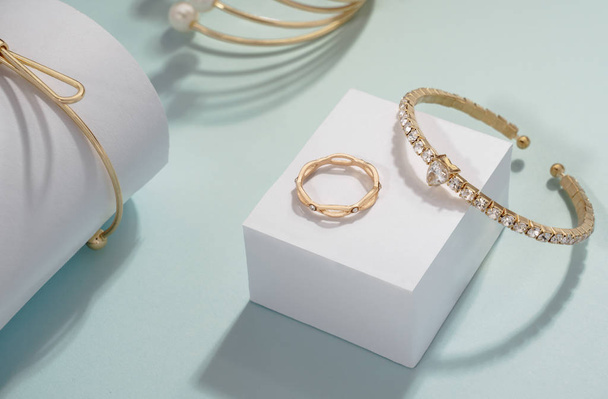 Golden gemstones bracelets set with golden ring on white cube display - Photo, Image