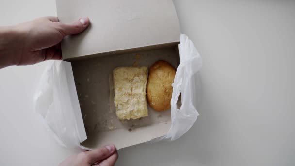 Руки чоловіка виймають булочку з білої паперової коробки, поміщені в білий пластиковий пакет
. - Кадри, відео