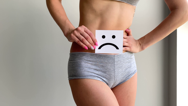 Stan zdrowia kobiety. Kobiecego ciała trzymając smutny uśmiech karty w pobliżu żołądka - Materiał filmowy, wideo