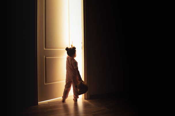 Little girl opens the door to the light in darkness - Foto, Bild