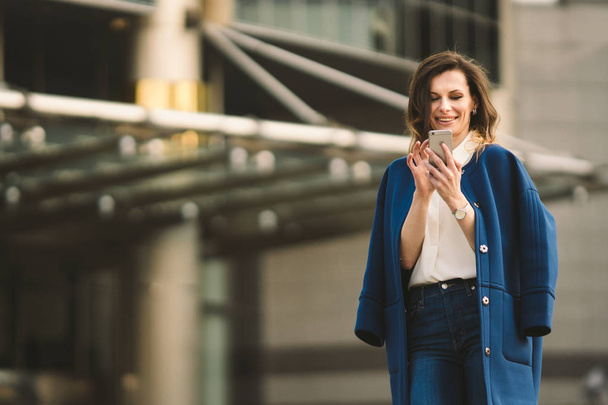Office buildings city people in suit. Caucasian businesswoman using smartphone with hand. Business concept. Portrait stylish business woman in fashionable clothes holding Phone near office building - Фото, изображение
