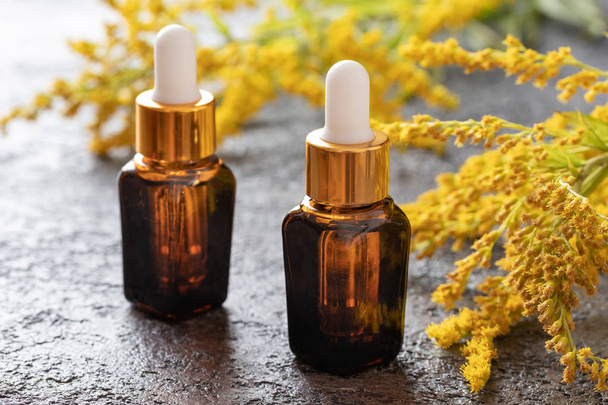 Bottles of goldenrod essential oil with fresh plant - Photo, Image