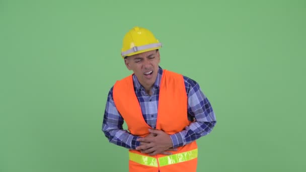 Stressed multi ethnic man construction worker having stomachache - Кадры, видео