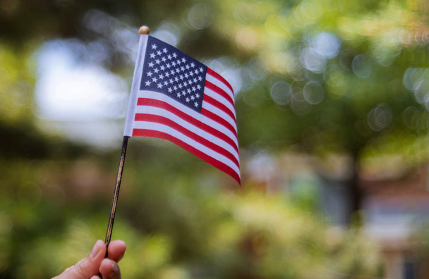 Θηλυκό που κρατά αμερικάνικη σημαία σε εξωτερικούς χώρους την όμορφη καλοκαιρινή μέρα. Ημέρα της ανεξαρτησίας - Φωτογραφία, εικόνα