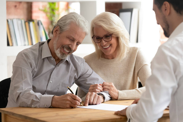 Счастливые пожилые клиенты подписывают договор страхования
 - Фото, изображение
