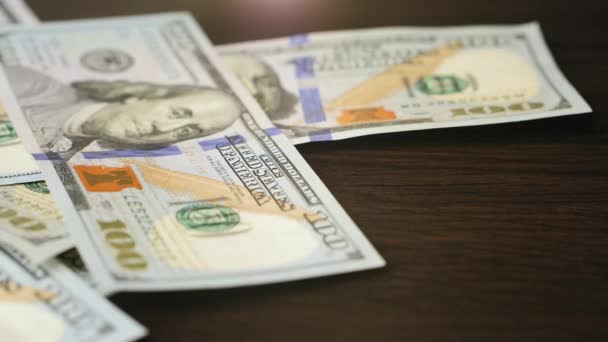 Stovka dolarových bankovek padajících na hnědý dřevěný stůl - Záběry, video