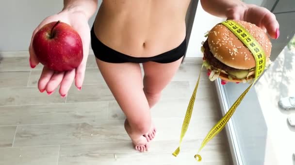 Dieta. Ritratto di donna vuole mangiare un hamburger, ma una bocca incollata, una nozione di dieta, cibo malsano, una volontà nella nutrizione
 - Filmati, video