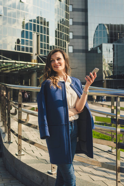 Office buildings city people in suit. Caucasian businesswoman using smartphone with hand. Business concept. Portrait stylish business woman in fashionable clothes holding Phone near office building - Photo, image
