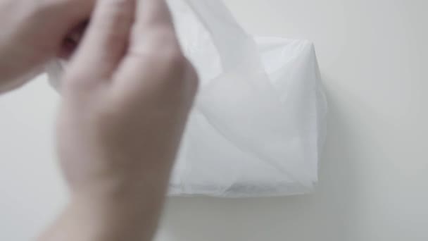 Mans mains mettre sac en plastique blanc avec boîte en papier blanc sur la table blanche
. - Séquence, vidéo
