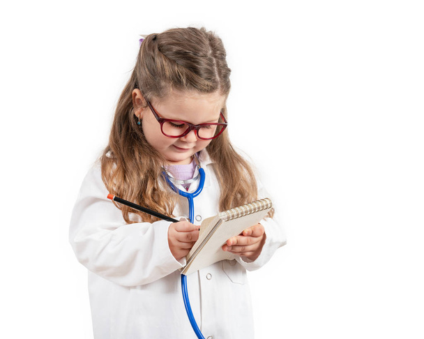 little cute girl in doctor costume holding sthetoscope on chalkboard. - Foto, immagini