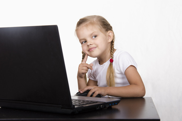 het meisje zitten aan de tafel, werken op een laptop, en keek gelijk - Foto, afbeelding