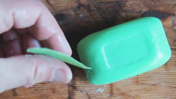 Gehydrateerde mensenhand houdt kleine restanten van groene zeep vast. Steekt een stuk zeep - Video