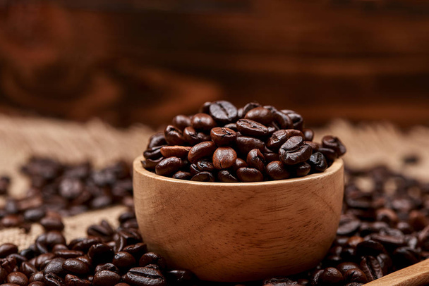 Wooden bowl with roasted coffee beans on rustic background. - Фото, зображення