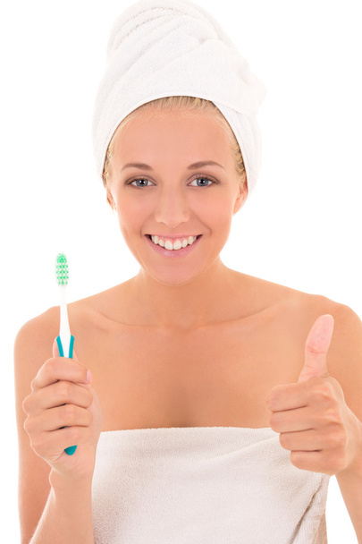 jolie femme avec une brosse à dents et serviette pouces vers le haut sur le blanc - Photo, image