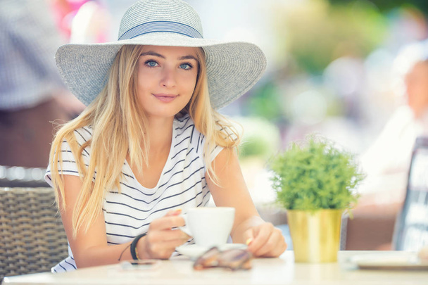 Beautiful girl drinking coffee in a cafe terrace. Summer portrai - Foto, imagen