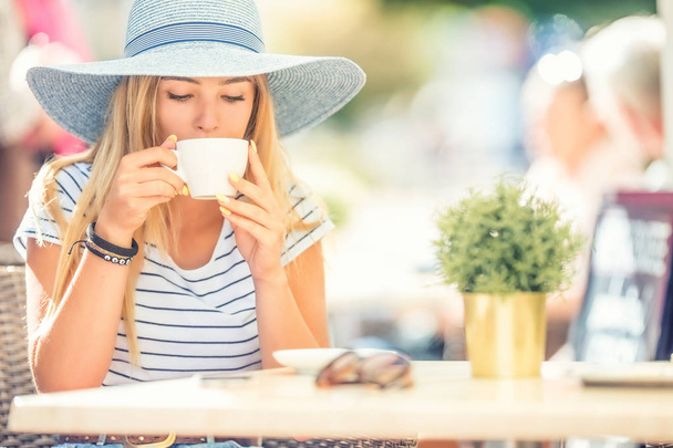 Beautiful girl drinking coffee in a cafe terrace. Summer portrai - Фото, зображення
