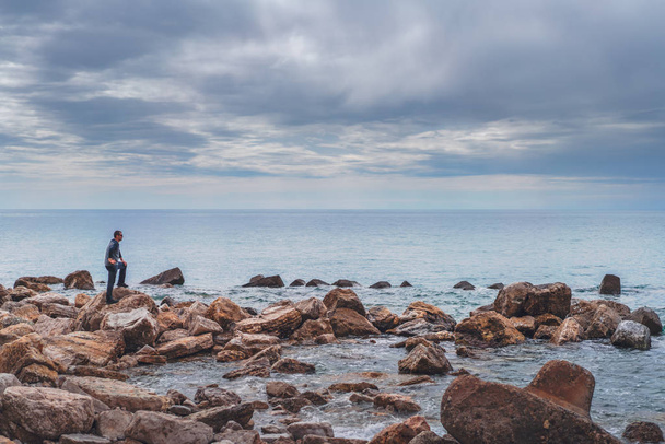 L'uomo che guarda il mare su una costa rocciosa - Foto, immagini