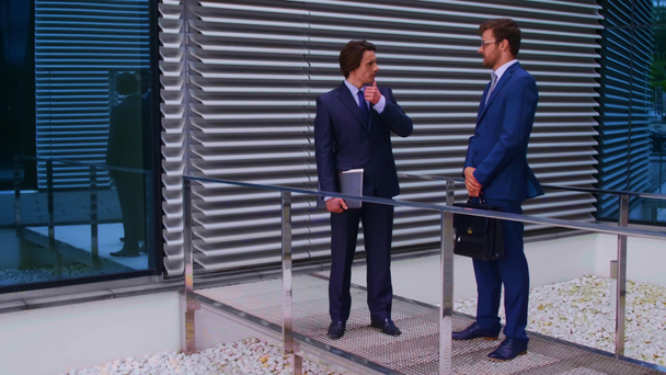 Hombres de negocios confiados hablando frente a un moderno edificio de oficinas. Empresario y su colega. Concepto de mercado bancario y financiero
. - Imágenes, Vídeo