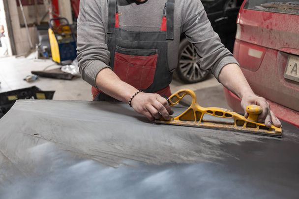 Man worker preparing for painting a car element using emery send - Photo, Image