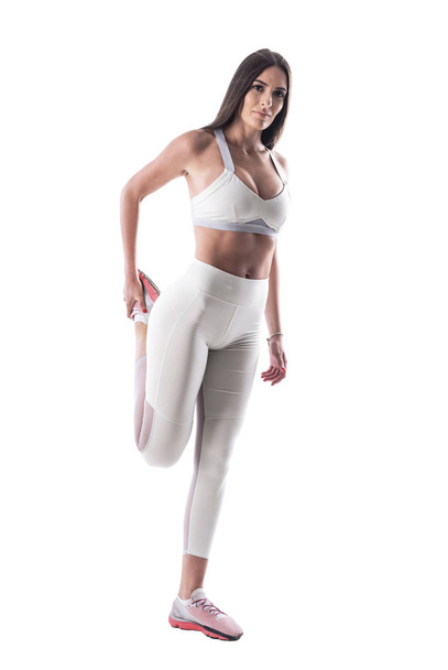 Sporty fiducioso in forma giovane donna in pantaloni bianchi yoga stretching muscoli delle gambe riscaldamento. Corpo intero isolato su sfondo bianco
.  - Foto, immagini